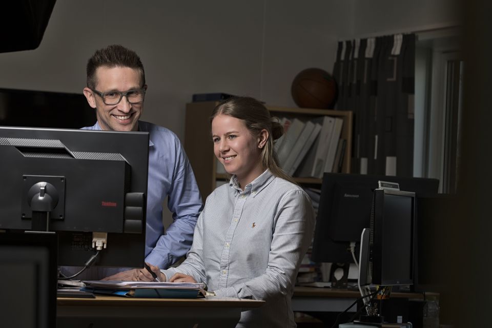 Two people looking at computer screen and smiling.