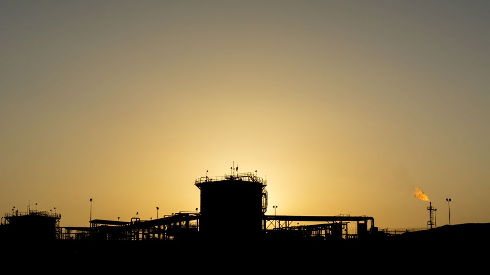 Silhouette of a manifold refinery plant in the oilfield at sunset.