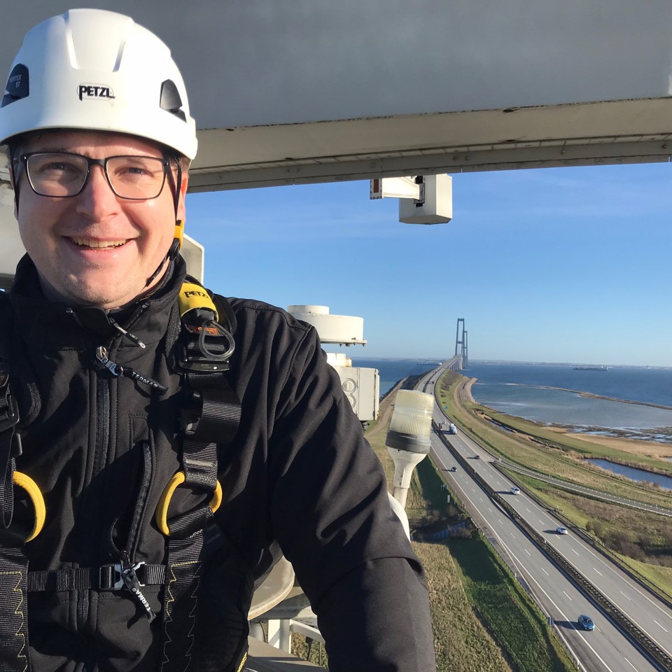 Terma Service Engineer smiling and standing on a radar tower near Storebælt.