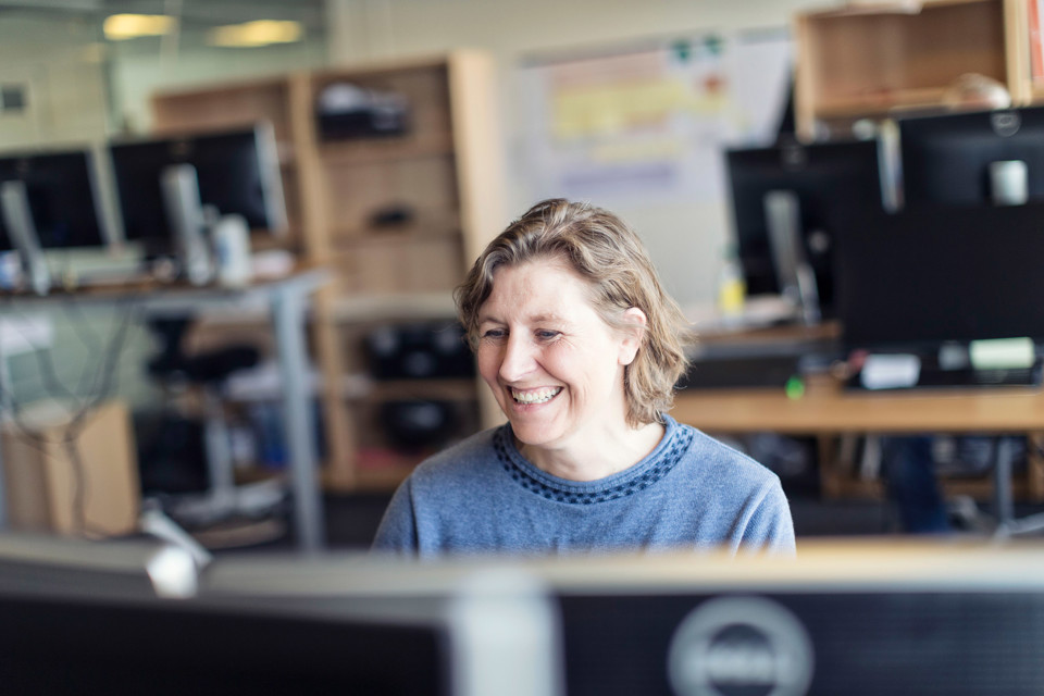 Terma employee working at a desk and smiling.