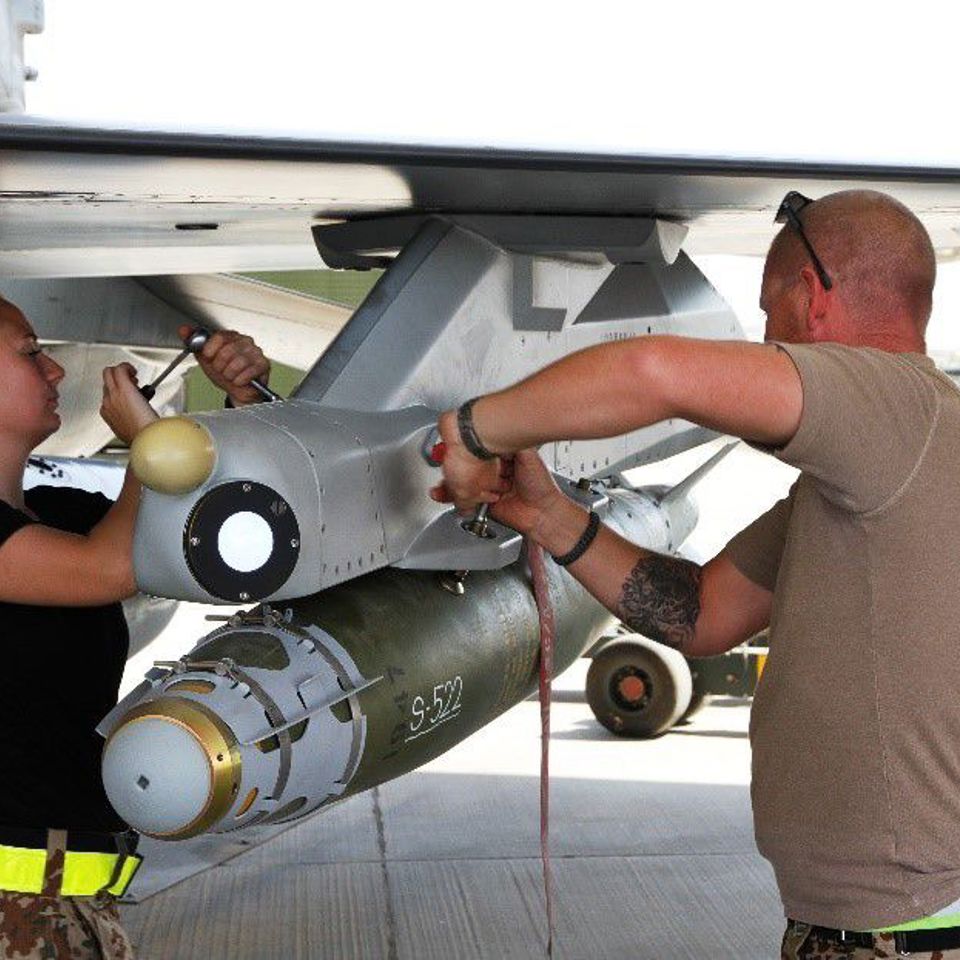 Mounting of missile to a pylon on a fighter jet on the ground.