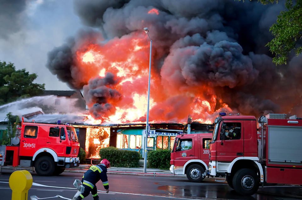 Fire trucks in front a building on fire.